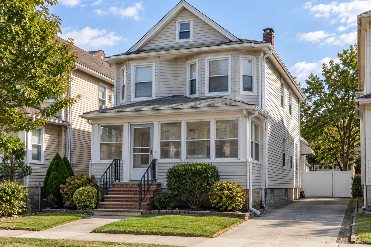 Frame two-family house in Bayonne with front porch, aluminum gutters and a leader down the corner