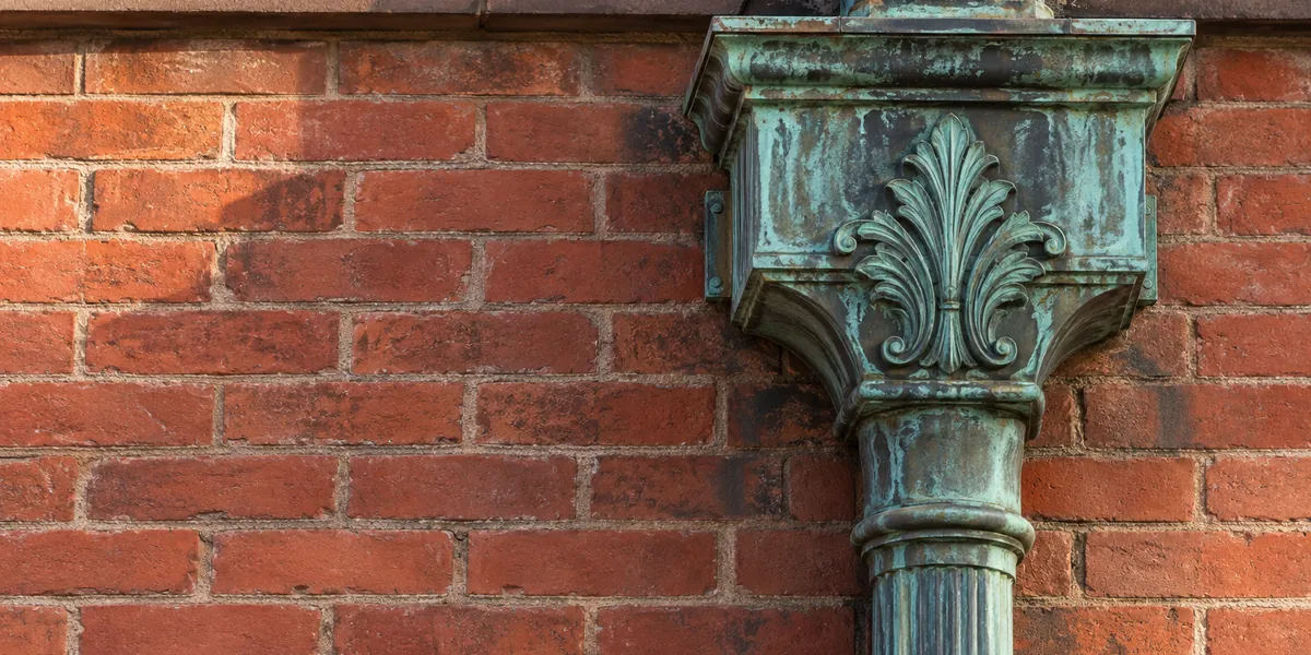 Close view of a copper conductor head and leader on a Jersey City brick facade