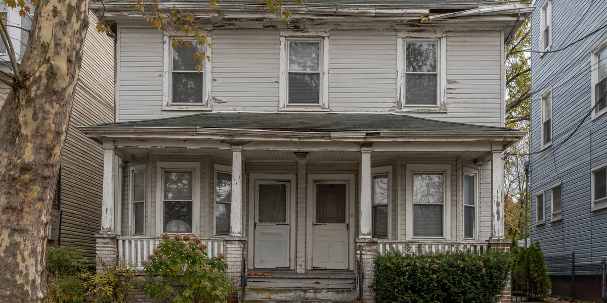 Aged sectional gutter pulling away from the fascia of a Jersey City two-family house